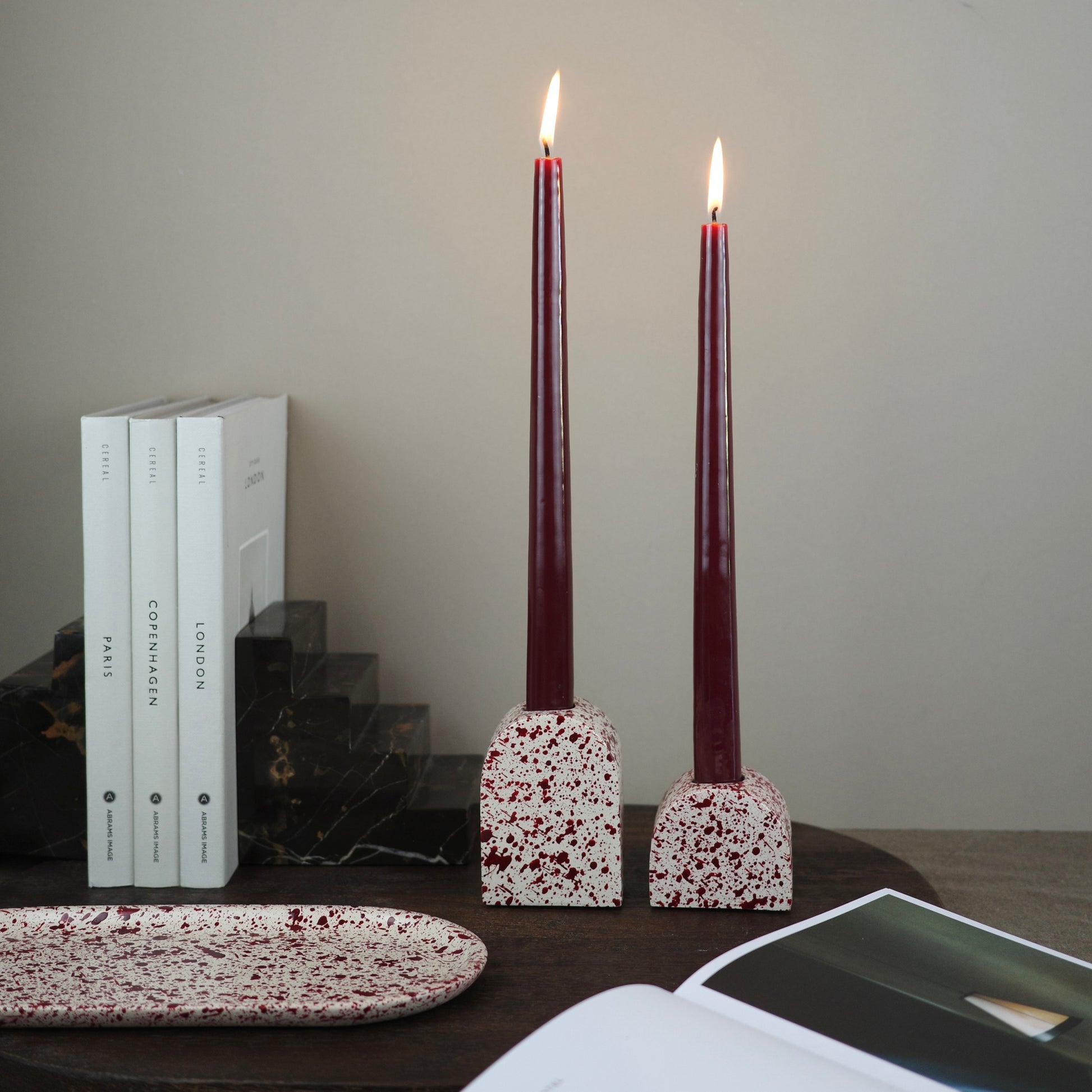 Burgundy paint splattered on a cream concrete small and large arch shaped candleholder