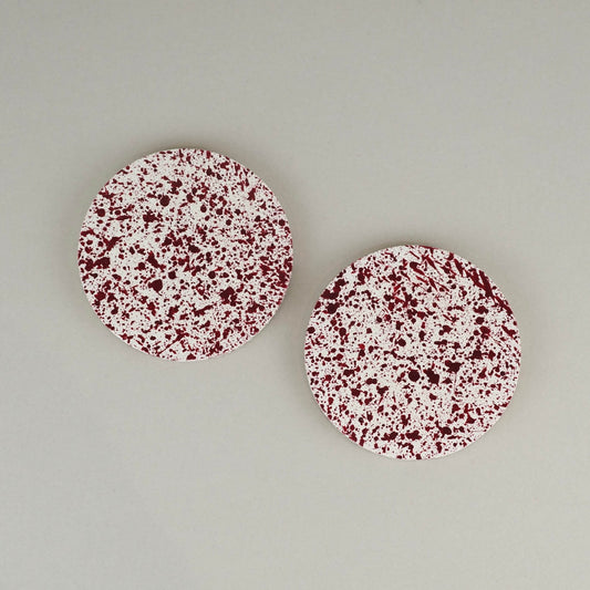 Burgundy paint splattered on a cream concrete circle round coaster set of 2