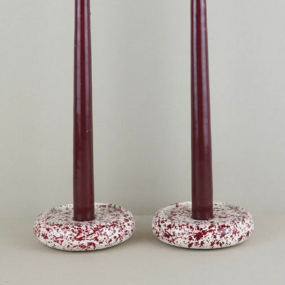 Burgundy paint splattered on a cream concrete circle shaped candleholder, stackable, close up