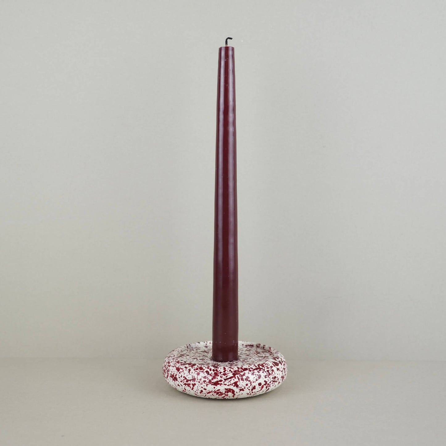 Burgundy paint splattered on a cream concrete circle shaped candleholder, stackable