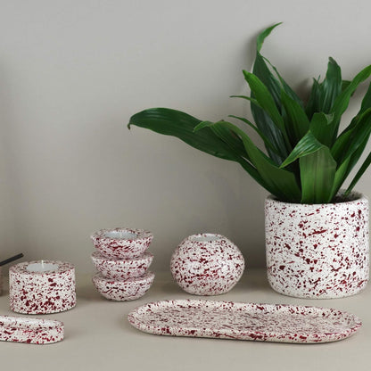 Burgundy paint splattered on a cream concrete homeware collection