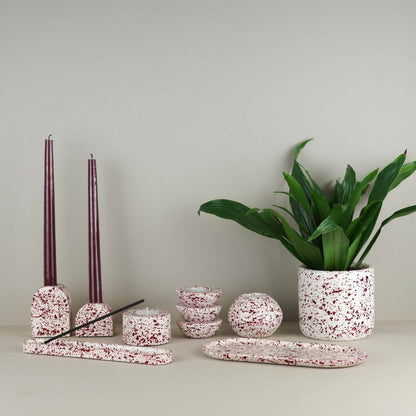 Burgundy paint splattered on a cream concrete homeware collection