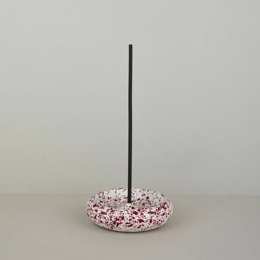 Burgundy paint splattered on a cream concrete circle shaped incense holder stackable