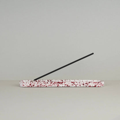 Burgundy paint splattered on a cream concrete long oblong incense holder