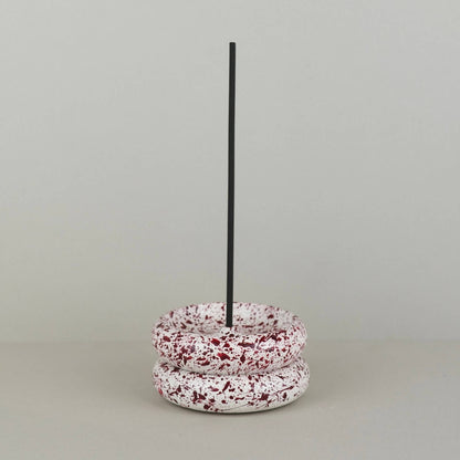 Burgundy paint splattered on a cream concrete circle shaped incense holder stackable, pair, stacked on top of each other