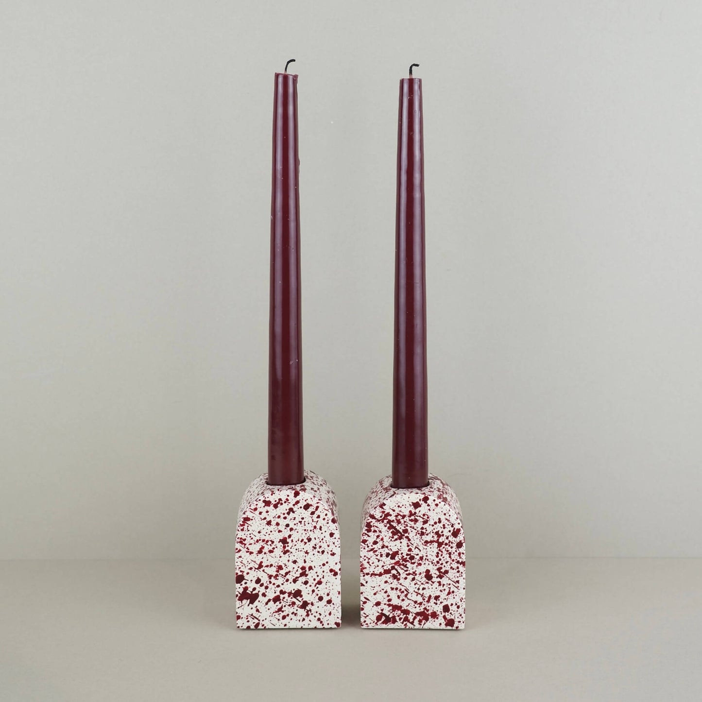 Burgundy paint splattered on a cream concrete large arch shaped candleholder, pair