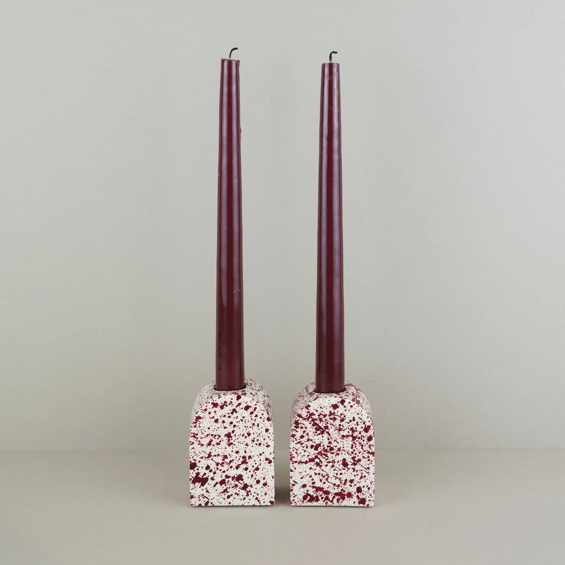 Burgundy paint splattered on a cream concrete large arch shaped candleholder, pair