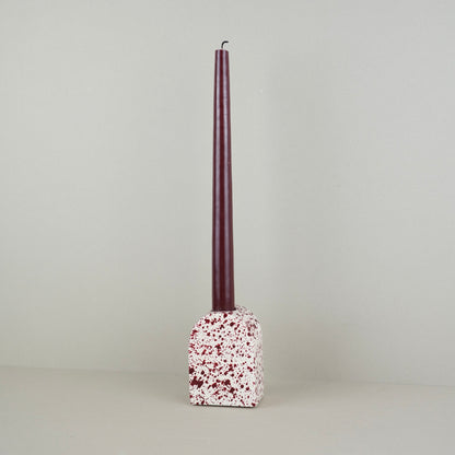 Burgundy paint splattered on a cream concrete large arch shaped candleholder