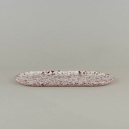 Burgundy paint splattered on a cream concrete oblong thin decorative tray