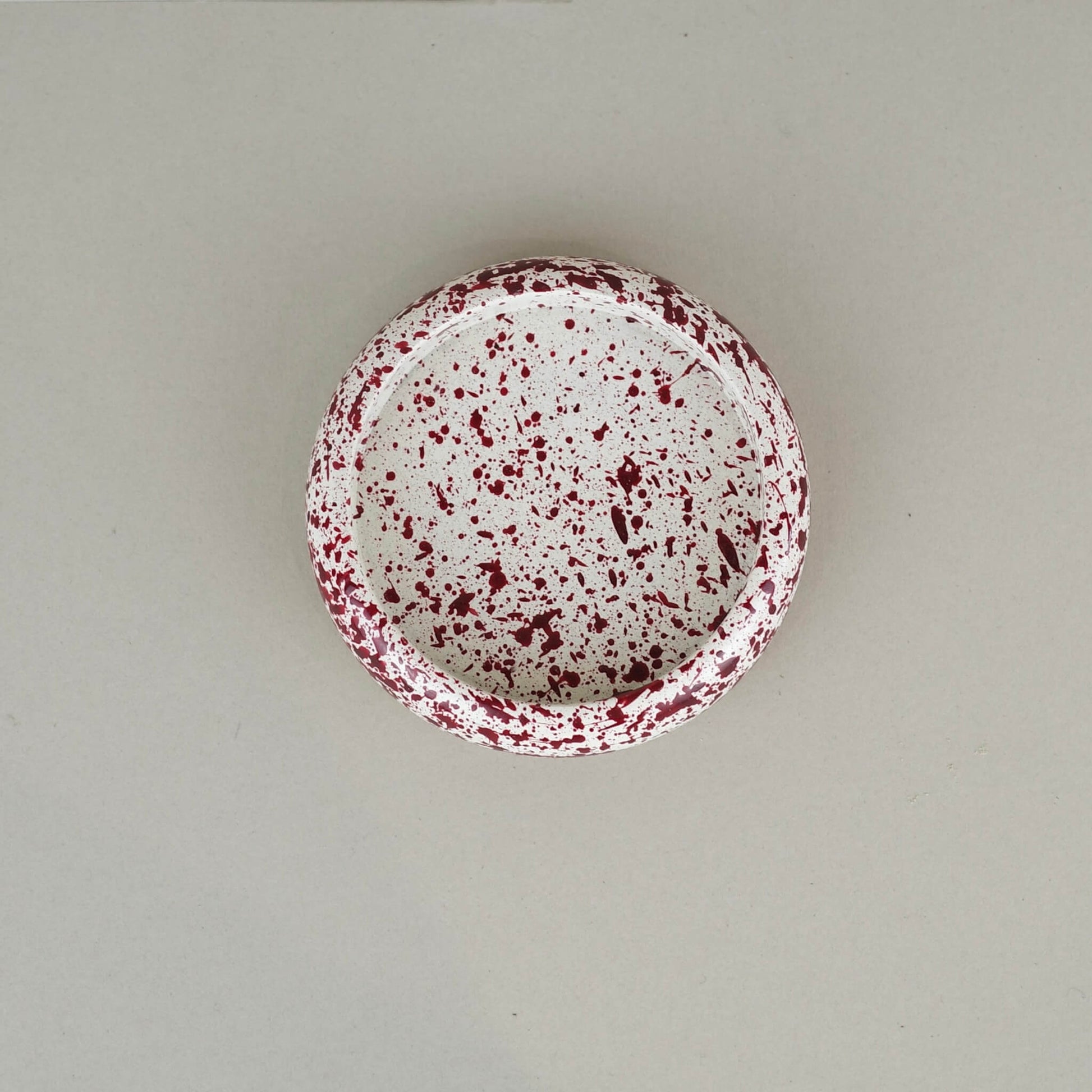 Burgundy paint splattered on a cream concrete circle shaped pillar candle holder stackable, top view