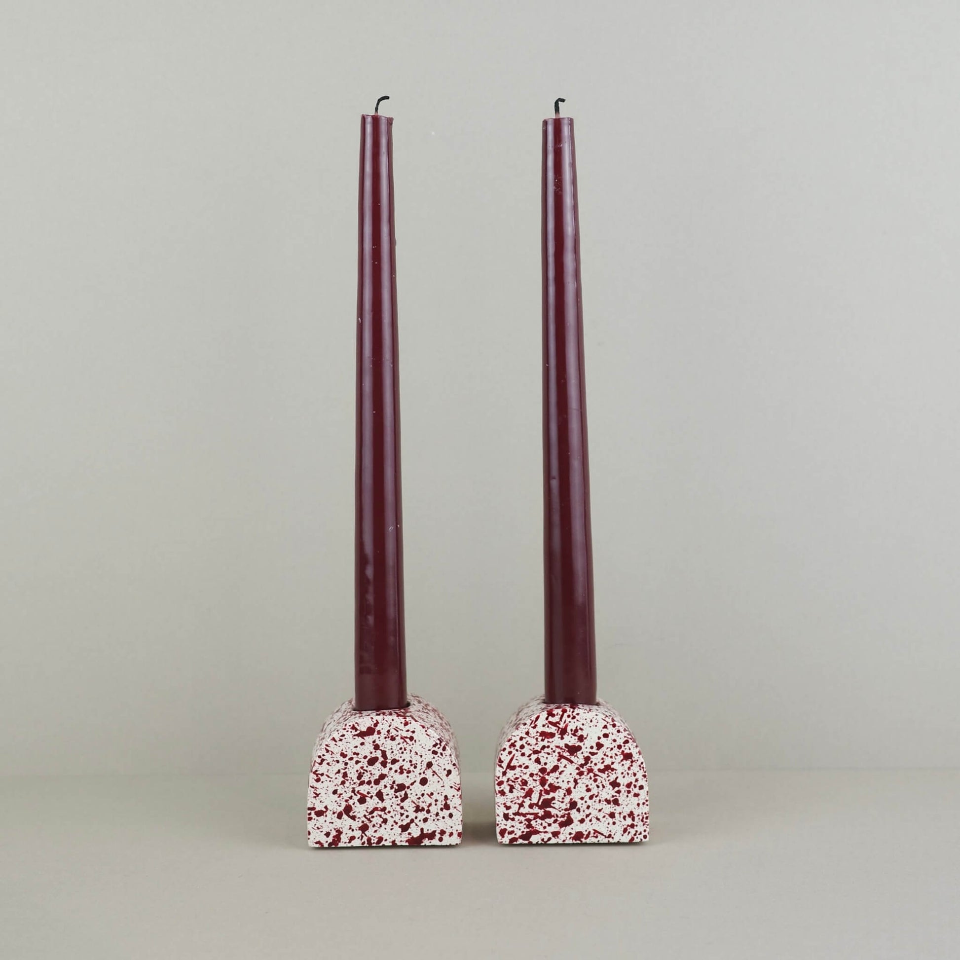 Burgundy paint splattered on a cream concrete small arch shaped candleholder, pair