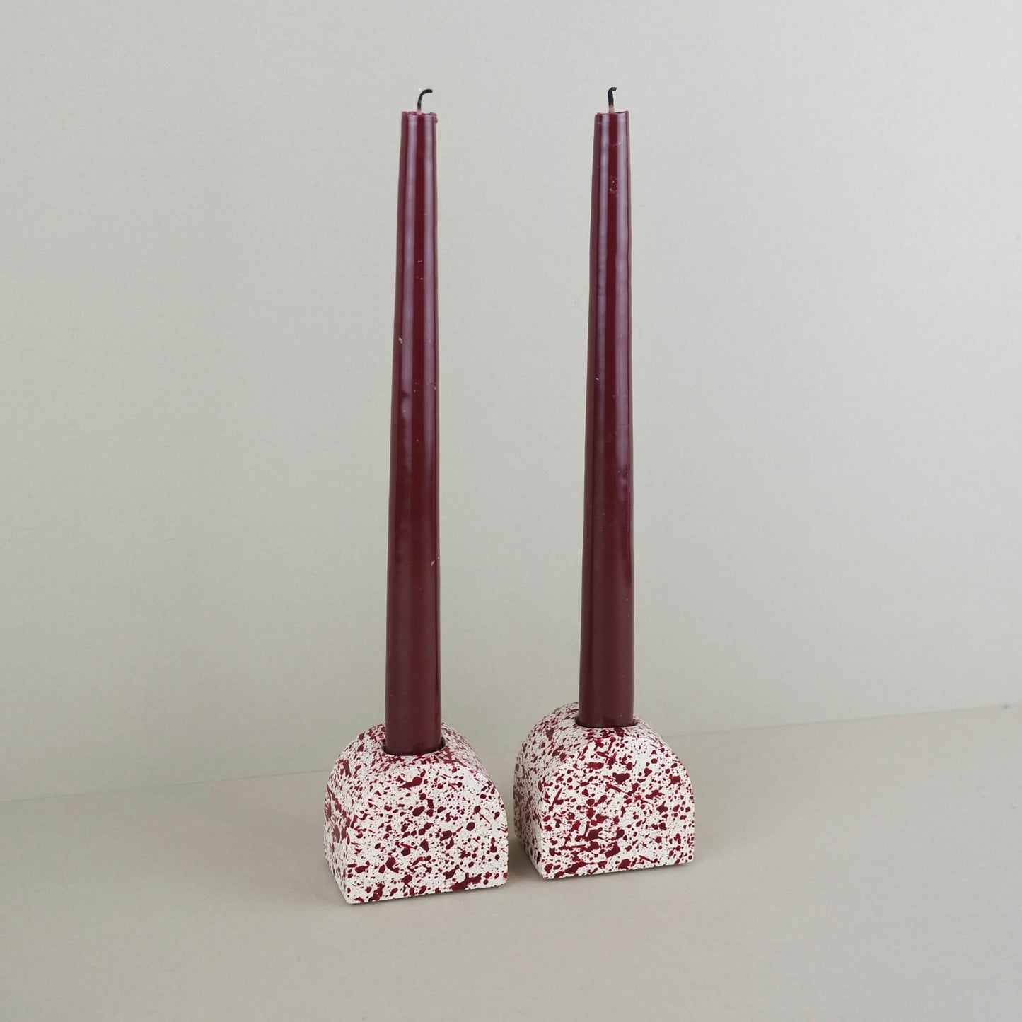 Burgundy paint splattered on a cream concrete small arch shaped candleholder, pair