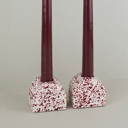 Burgundy paint splattered on a cream concrete small arch shaped candleholder, pair, close