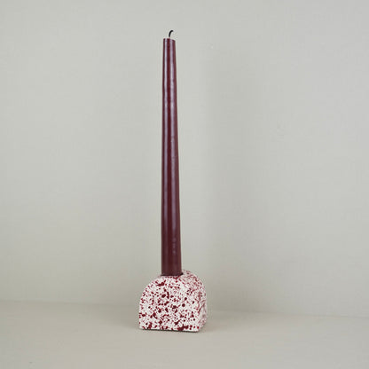 Burgundy paint splattered on a cream concrete small arch shaped candleholder