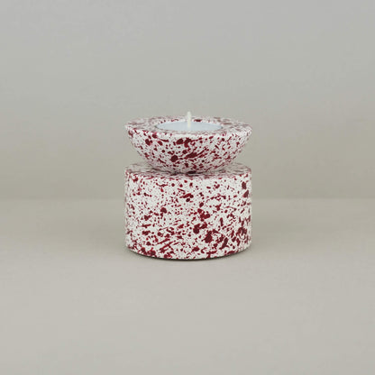 Burgundy paint splattered on a cream concrete half sphere shaped tealight holder, stacked on a cylinder tealight holder