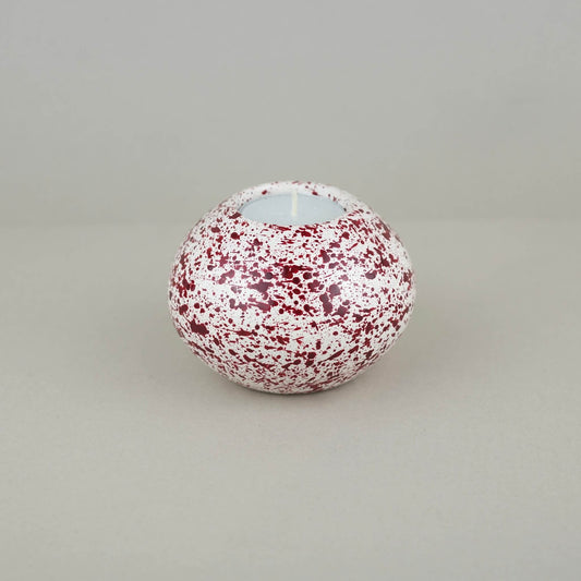 Burgundy paint splattered on a cream concrete sphere shaped tealight holder