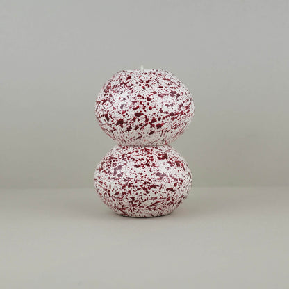 Burgundy paint splattered on a cream concrete sphere shaped tealight holder, two stacked on top of each other