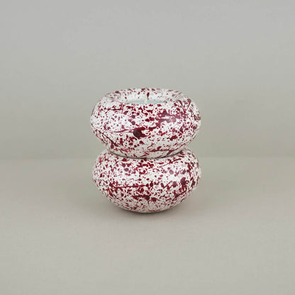 Burgundy paint splattered on a cream concrete sunken sphere shaped tealight holder 2 stacked on top of each other