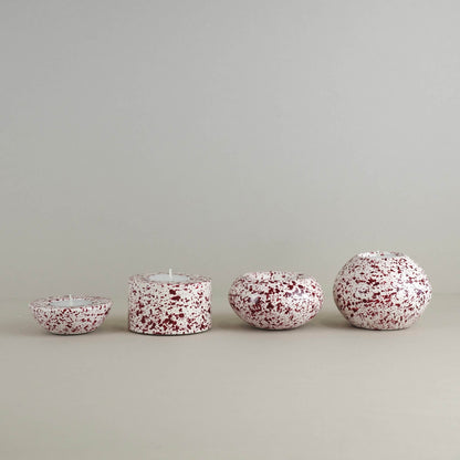 Burgundy paint splattered on a cream concrete tealight holder, collection of sphere shapes