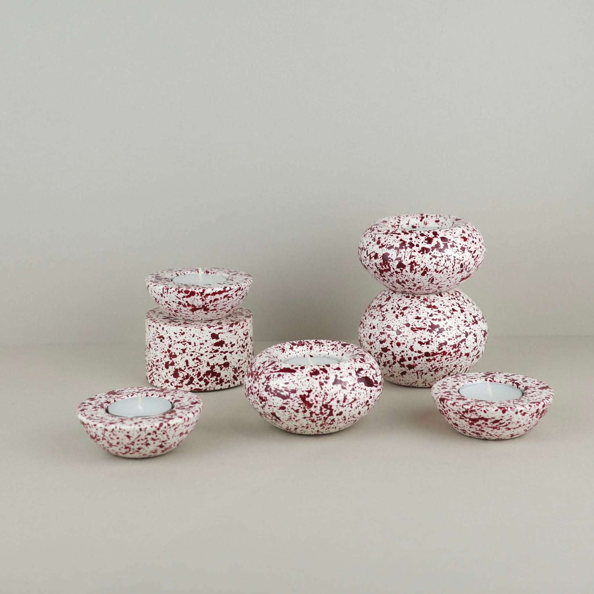 Burgundy paint splattered on a cream concrete tealight holder, collection of sphere shapes