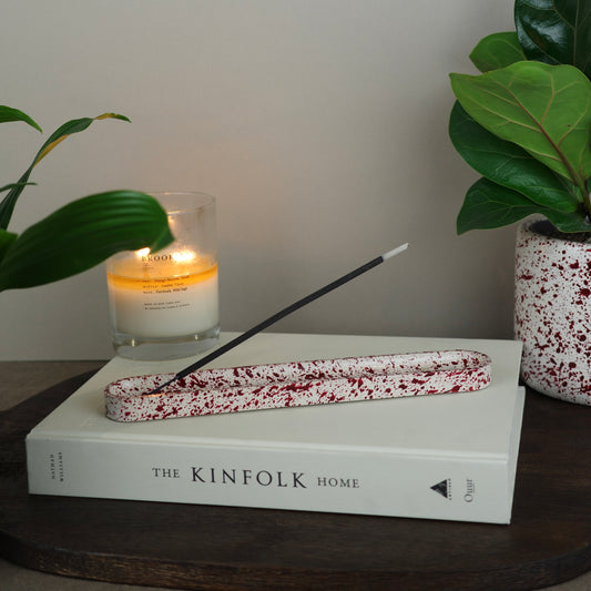 Burgundy paint splattered on a cream concrete long oblong incense holder