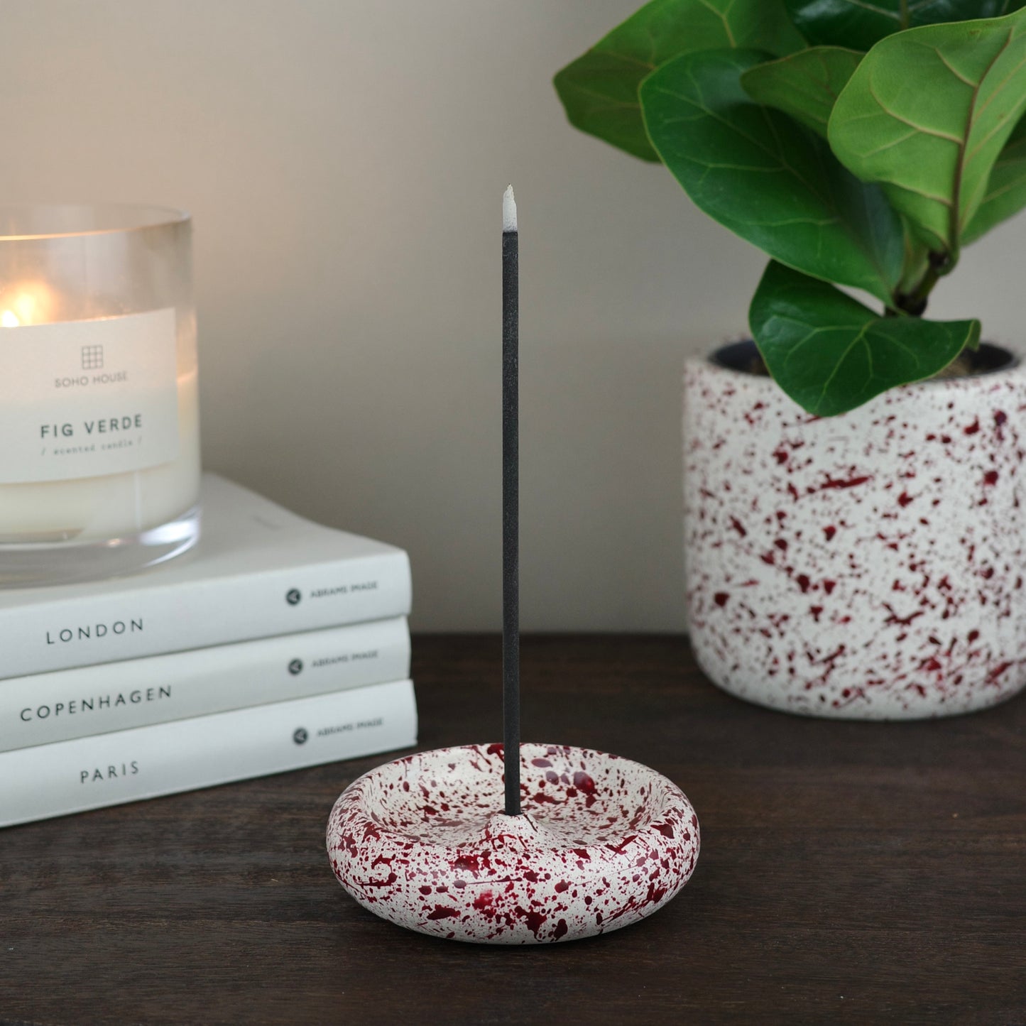 Burgundy paint splattered on a cream concrete circle shaped incense holder stackable