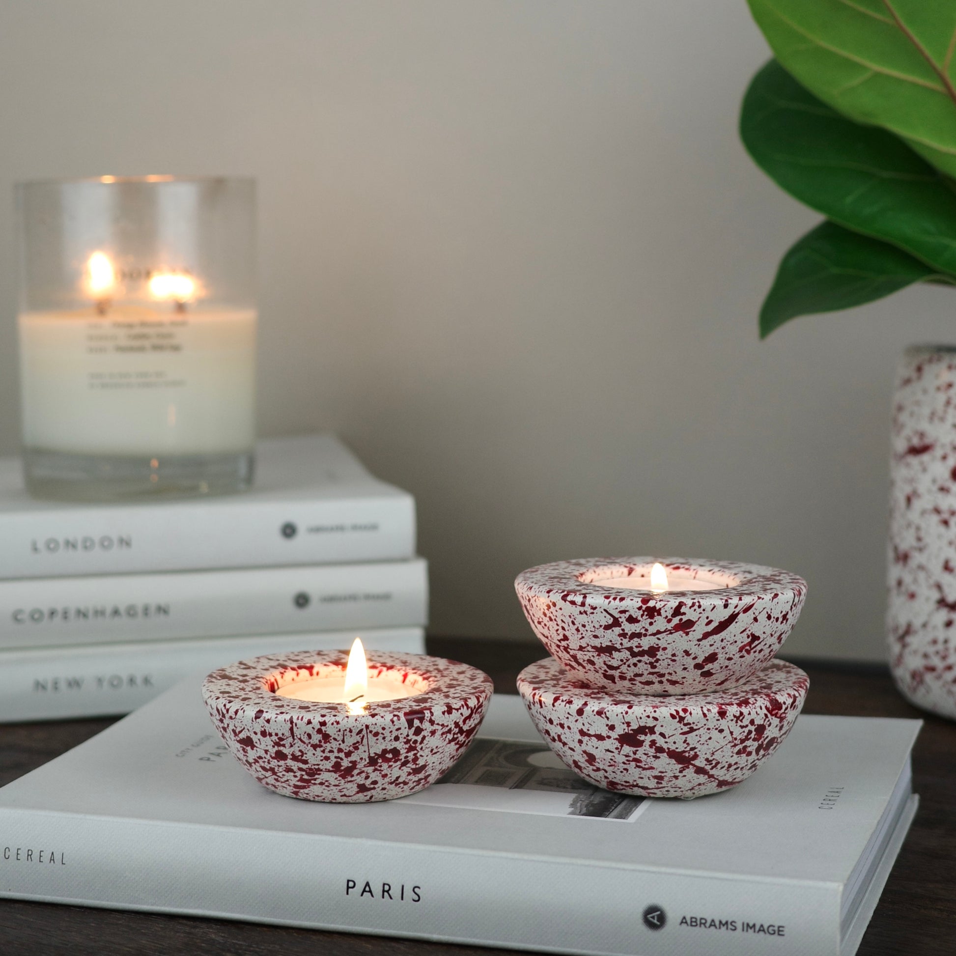 Burgundy paint splattered on a cream concrete half sphere shaped tealight holder