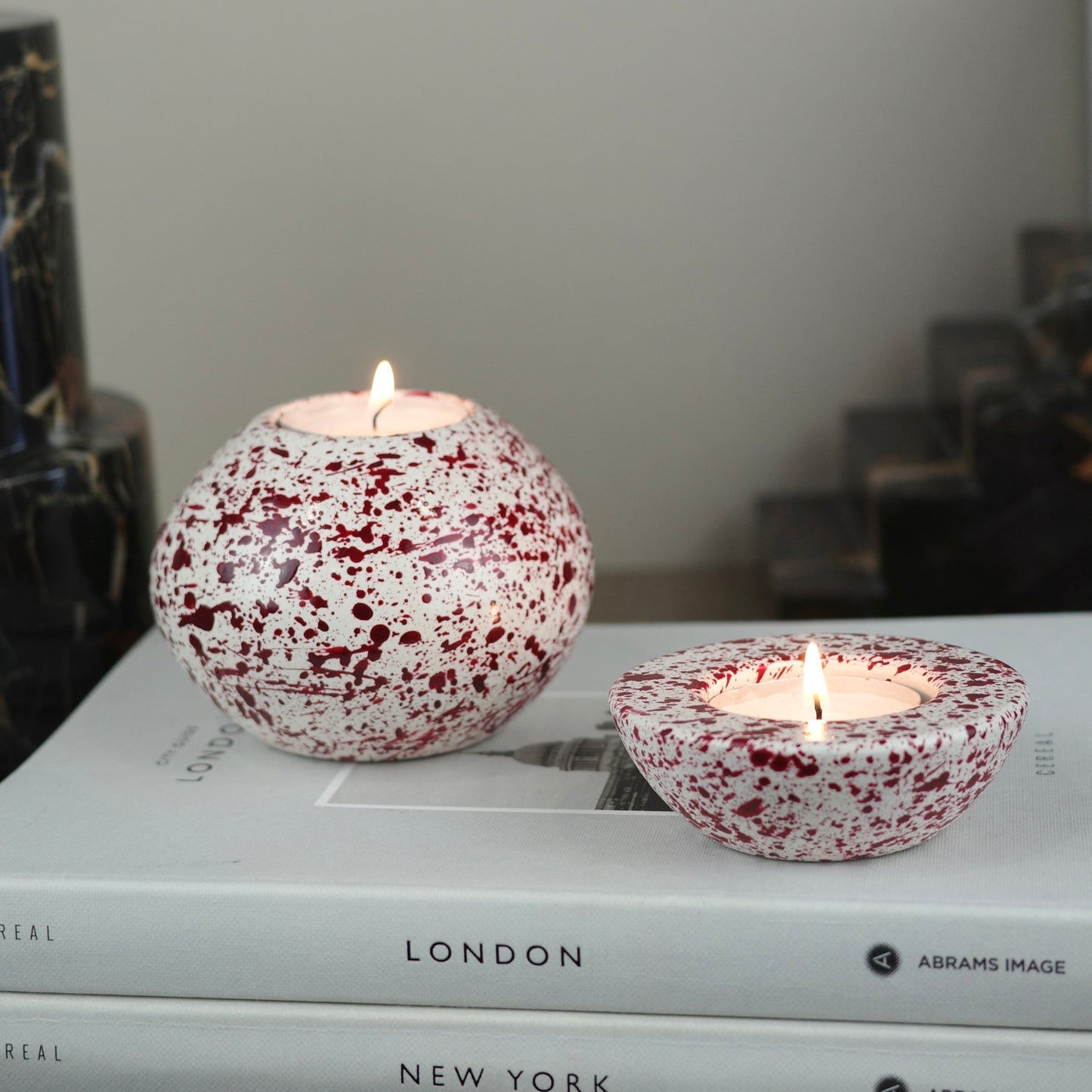 Burgundy paint splattered on a cream concrete sphere shaped tealight holder and half sphere tealight