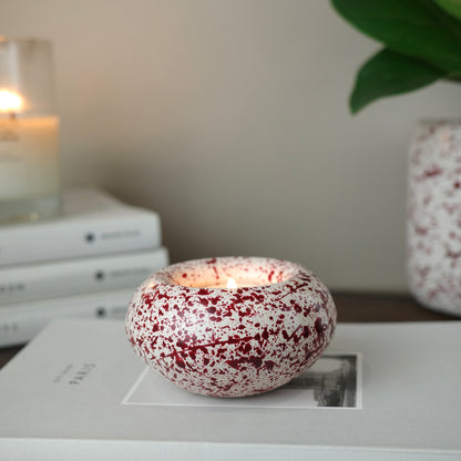 Burgundy paint splattered on a cream concrete sunken sphere shaped tealight holder